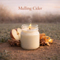 Candle in a jar with apples, cinnamon sticks, and star anise on a grassy background with 'Mulling Cider' text.