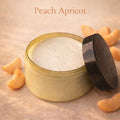 Open jar of Peach Apricot cream with slices of peach around it on a beige background